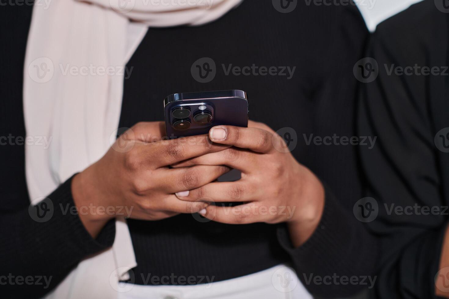 Captured in a close-up moment, a girl in hijab skillfully engages with her smartphone, reflecting a contemporary lifestyle where digital connectivity seamlessly intertwines with cultural expression photo