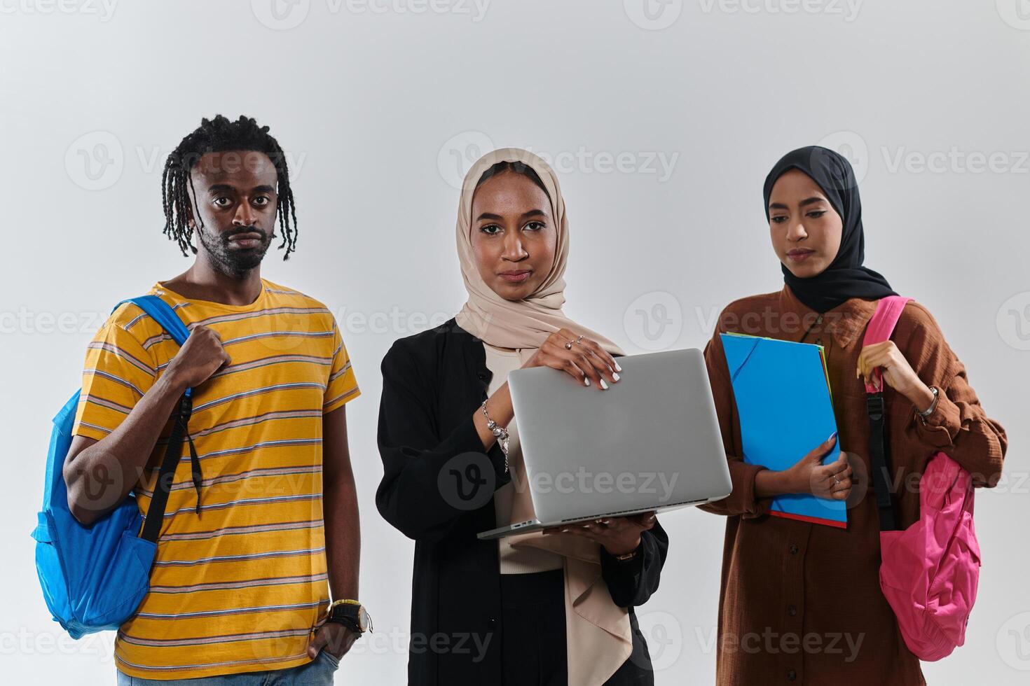 A group of students, including an African American student and two hijab-wearing women, stand united against a pristine white background, symbolizing a harmonious blend of cultures and backgrounds in photo