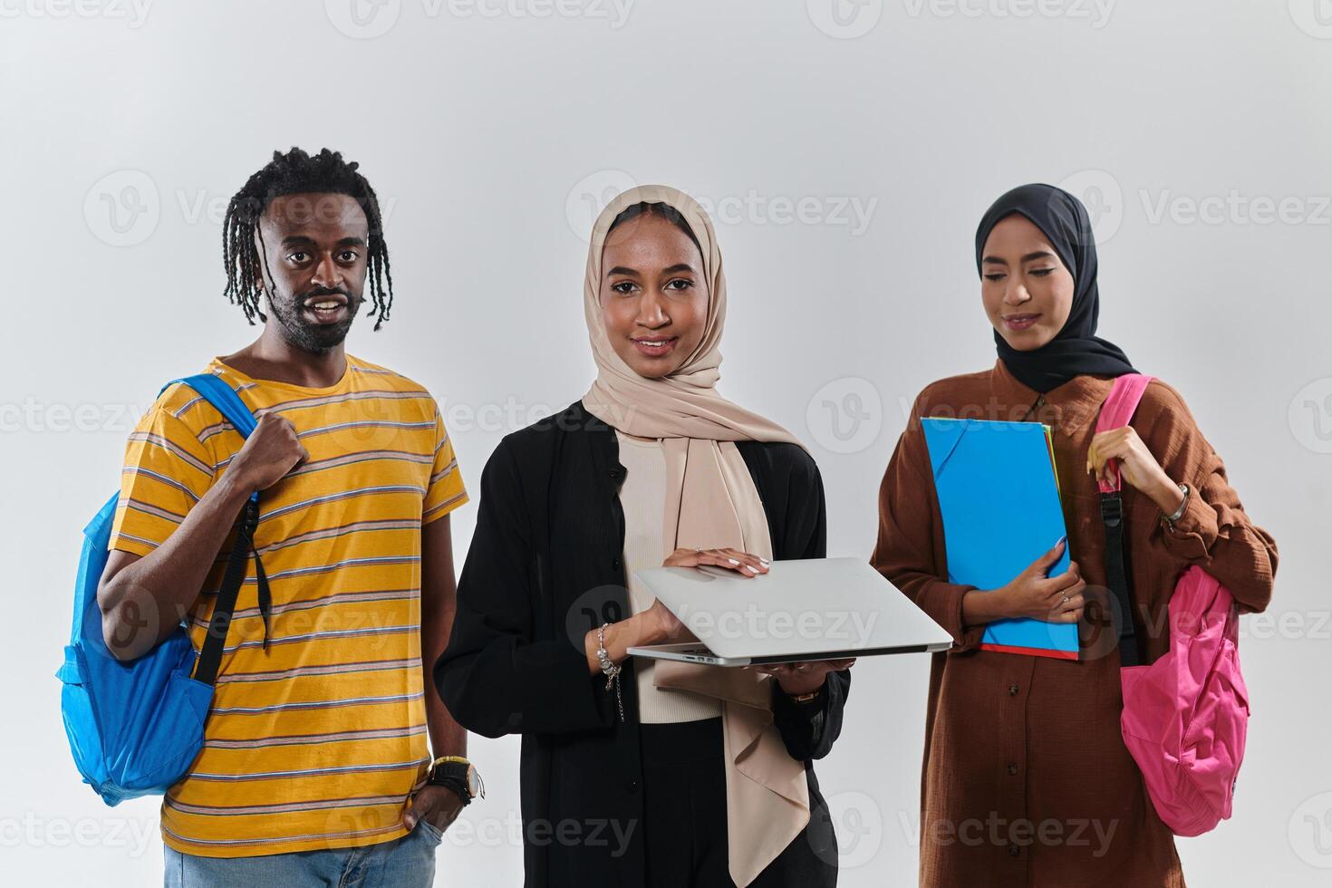 A group of students, including an African American student and two hijab-wearing women, stand united against a pristine white background, symbolizing a harmonious blend of cultures and backgrounds in photo
