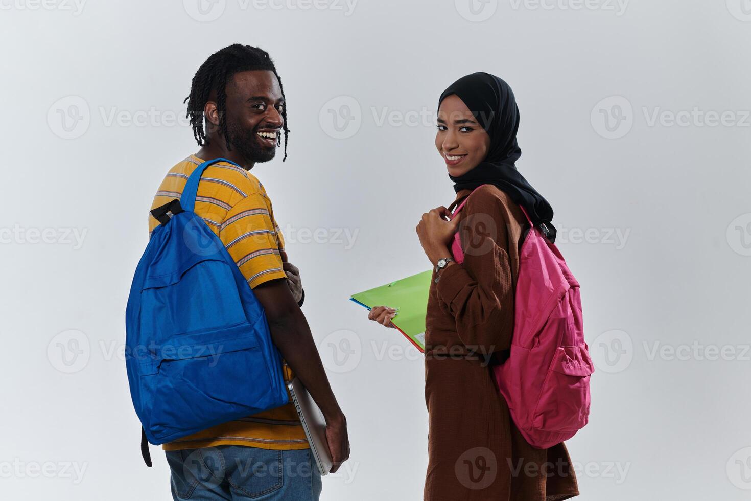 African American student collaborates with his Muslim colleague, who diligently works on her laptop, symbolizing a blend of diversity, modern learning, and cooperative spirit against a serene white photo
