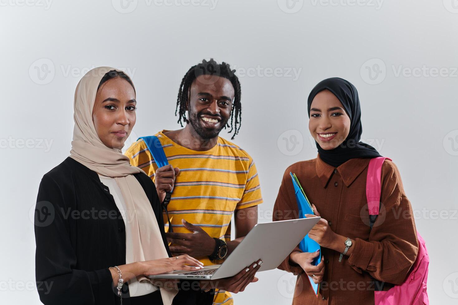 A group of students, including an African American student and two hijab-wearing women, stand united against a pristine white background, symbolizing a harmonious blend of cultures and backgrounds in photo