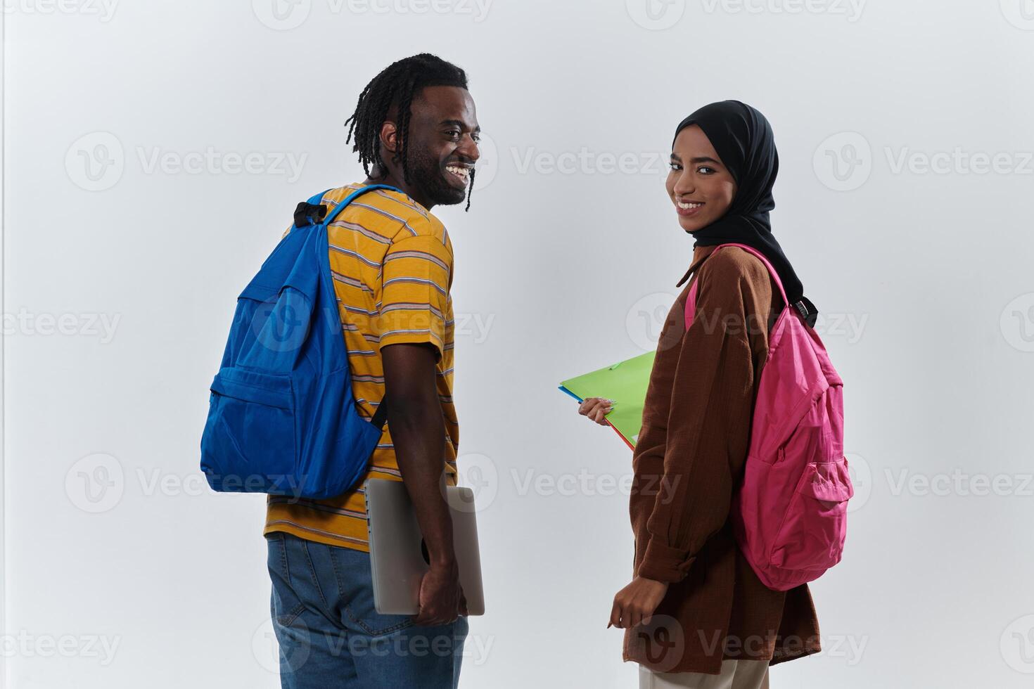 African American student collaborates with his Muslim colleague, who diligently works on her laptop, symbolizing a blend of diversity, modern learning, and cooperative spirit against a serene white photo