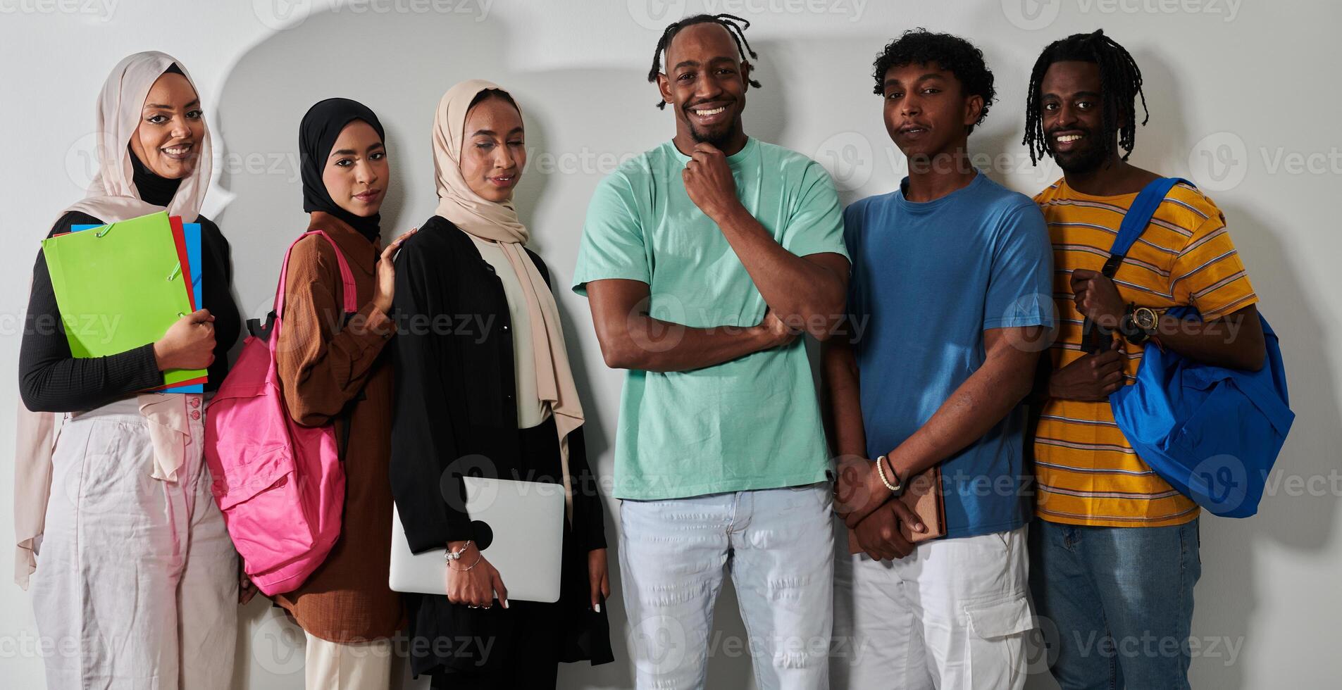 In a vibrant display of educational diversity, a group of students strikes a pose against a clean white background, holding backpacks, laptops, and tablets, symbolizing a blend of modern technology photo