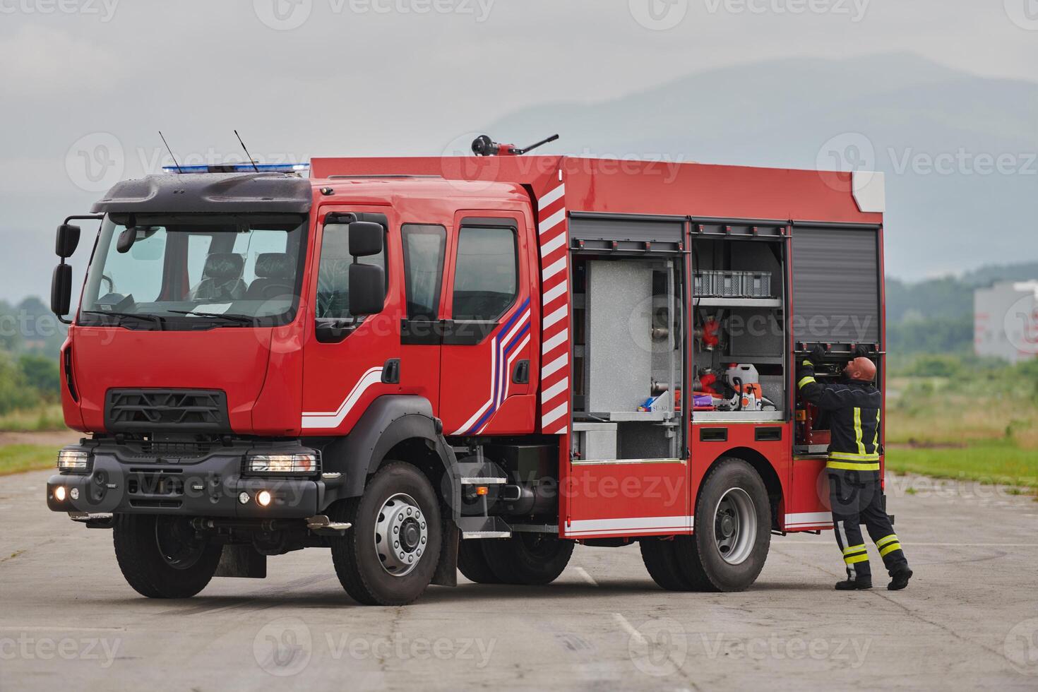 A firefighter meticulously prepares a modern firetruck for a mission to evacuate and respond to dangerous situations, showcasing the utmost dedication to safety and readiness in the face of a fire photo