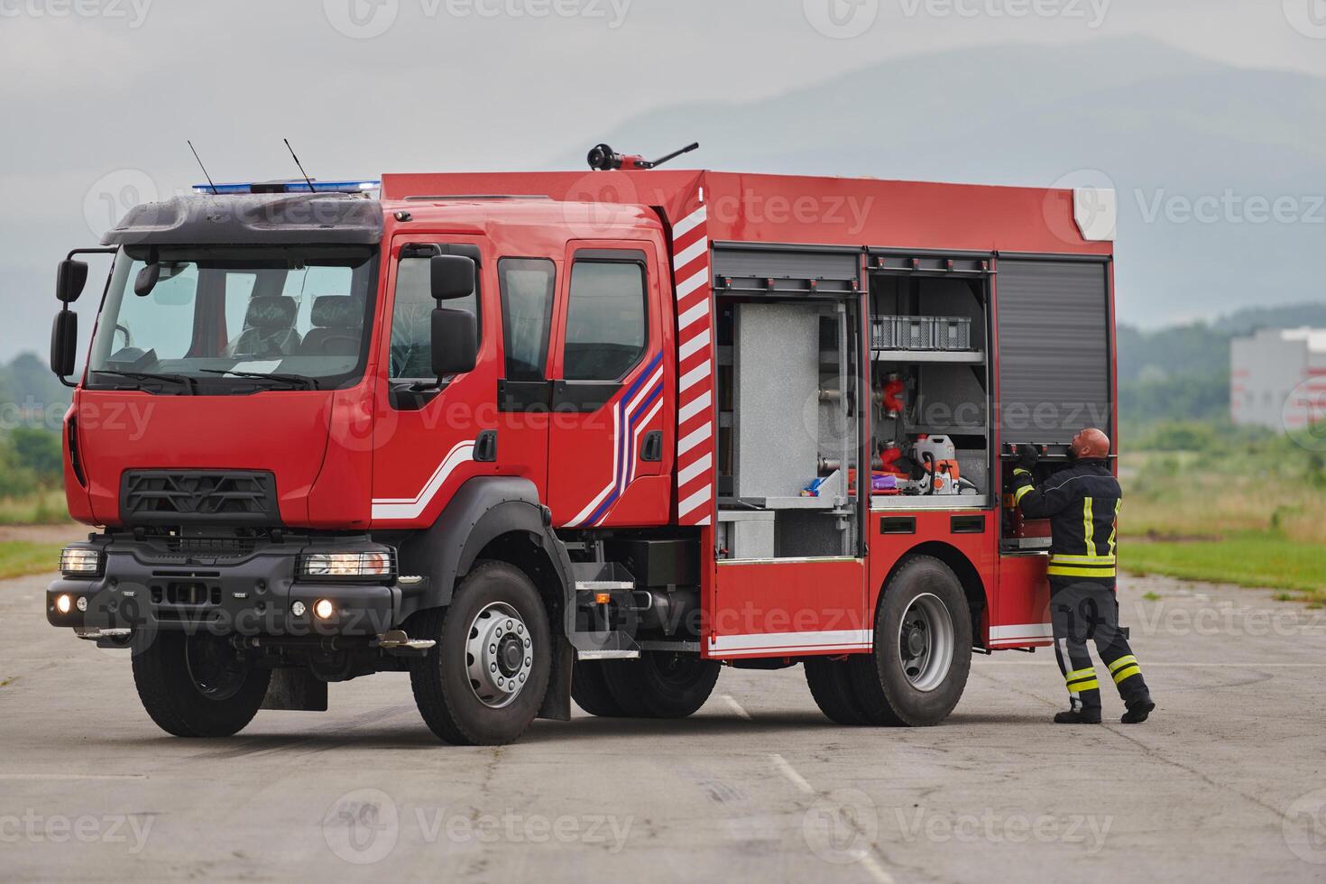 A firefighter meticulously prepares a modern firetruck for a mission to evacuate and respond to dangerous situations, showcasing the utmost dedication to safety and readiness in the face of a fire photo