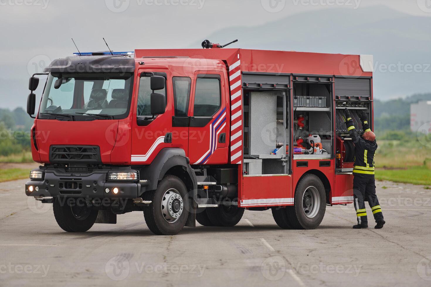 A firefighter meticulously prepares a modern firetruck for a mission to evacuate and respond to dangerous situations, showcasing the utmost dedication to safety and readiness in the face of a fire photo