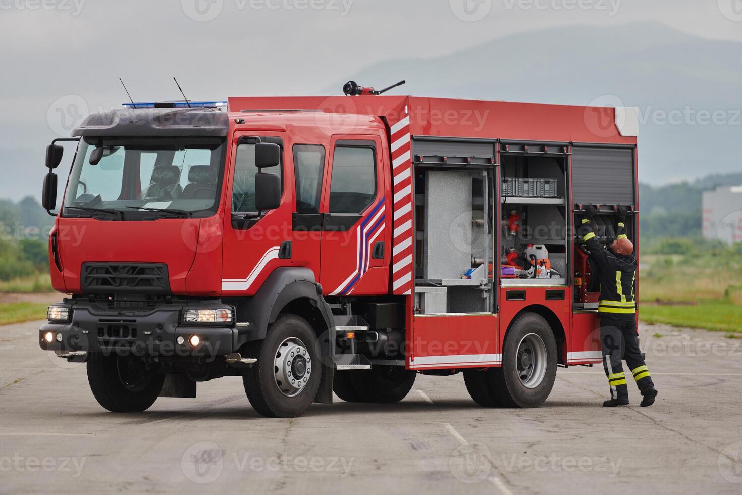 A firefighter meticulously prepares a modern firetruck for a mission to evacuate and respond to dangerous situations, showcasing the utmost dedication to safety and readiness in the face of a fire photo