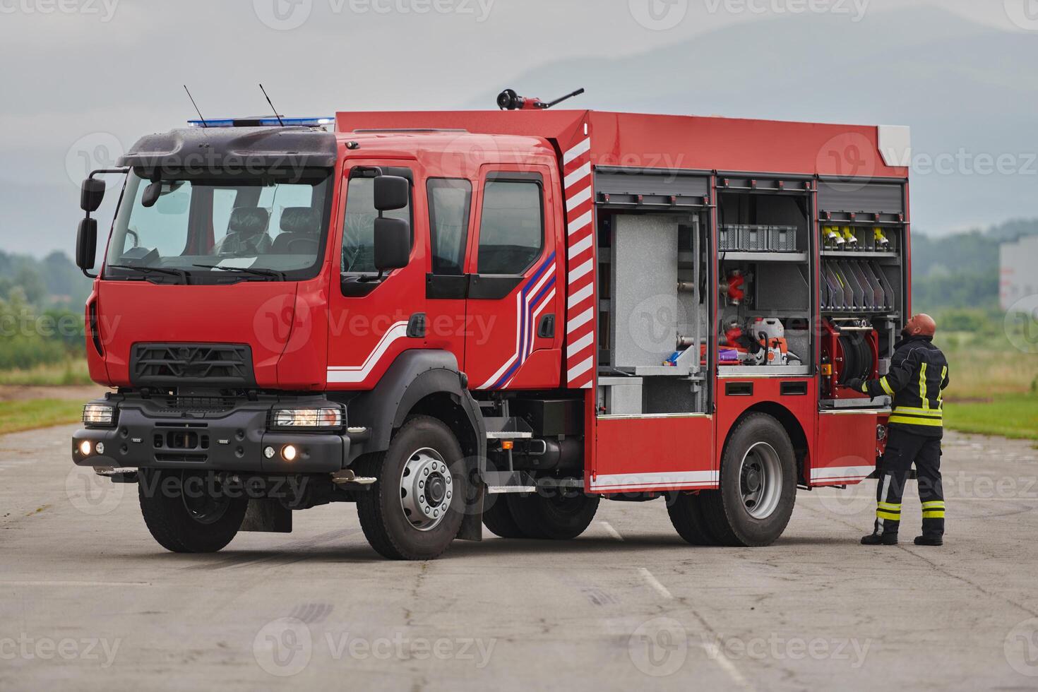 A firefighter meticulously prepares a modern firetruck for a mission to evacuate and respond to dangerous situations, showcasing the utmost dedication to safety and readiness in the face of a fire photo