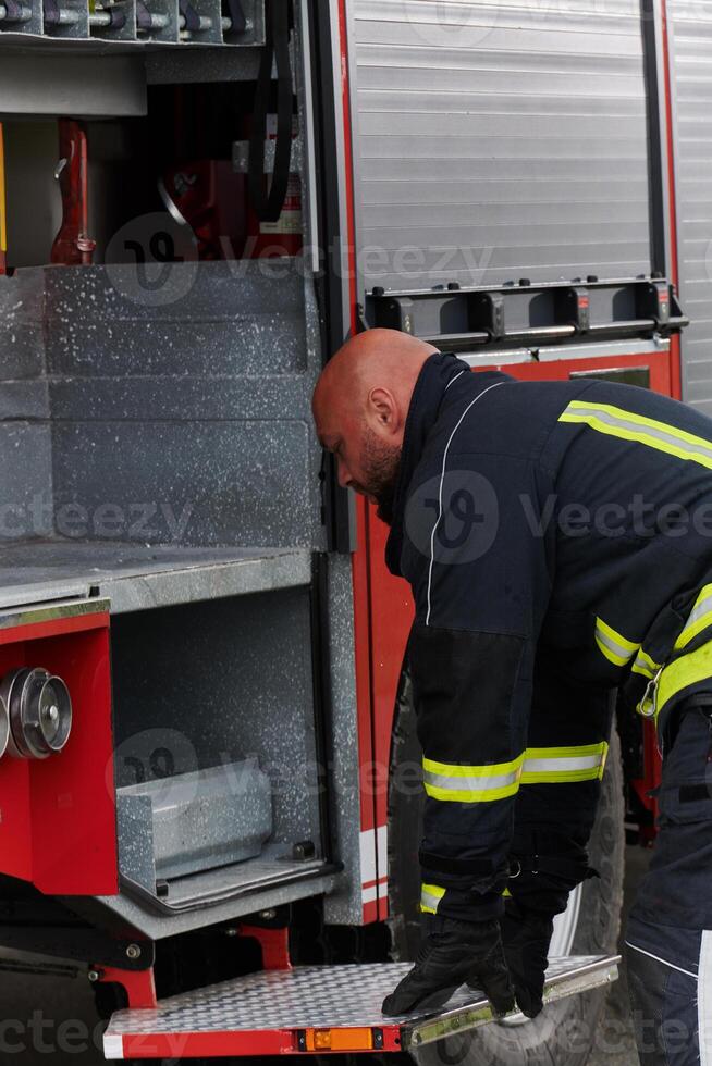 A firefighter meticulously prepares a modern firetruck for a mission to evacuate and respond to dangerous situations, showcasing the utmost dedication to safety and readiness in the face of a fire photo