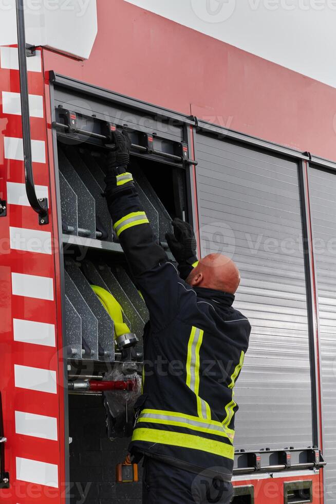 A firefighter meticulously prepares a modern firetruck for a mission to evacuate and respond to dangerous situations, showcasing the utmost dedication to safety and readiness in the face of a fire photo