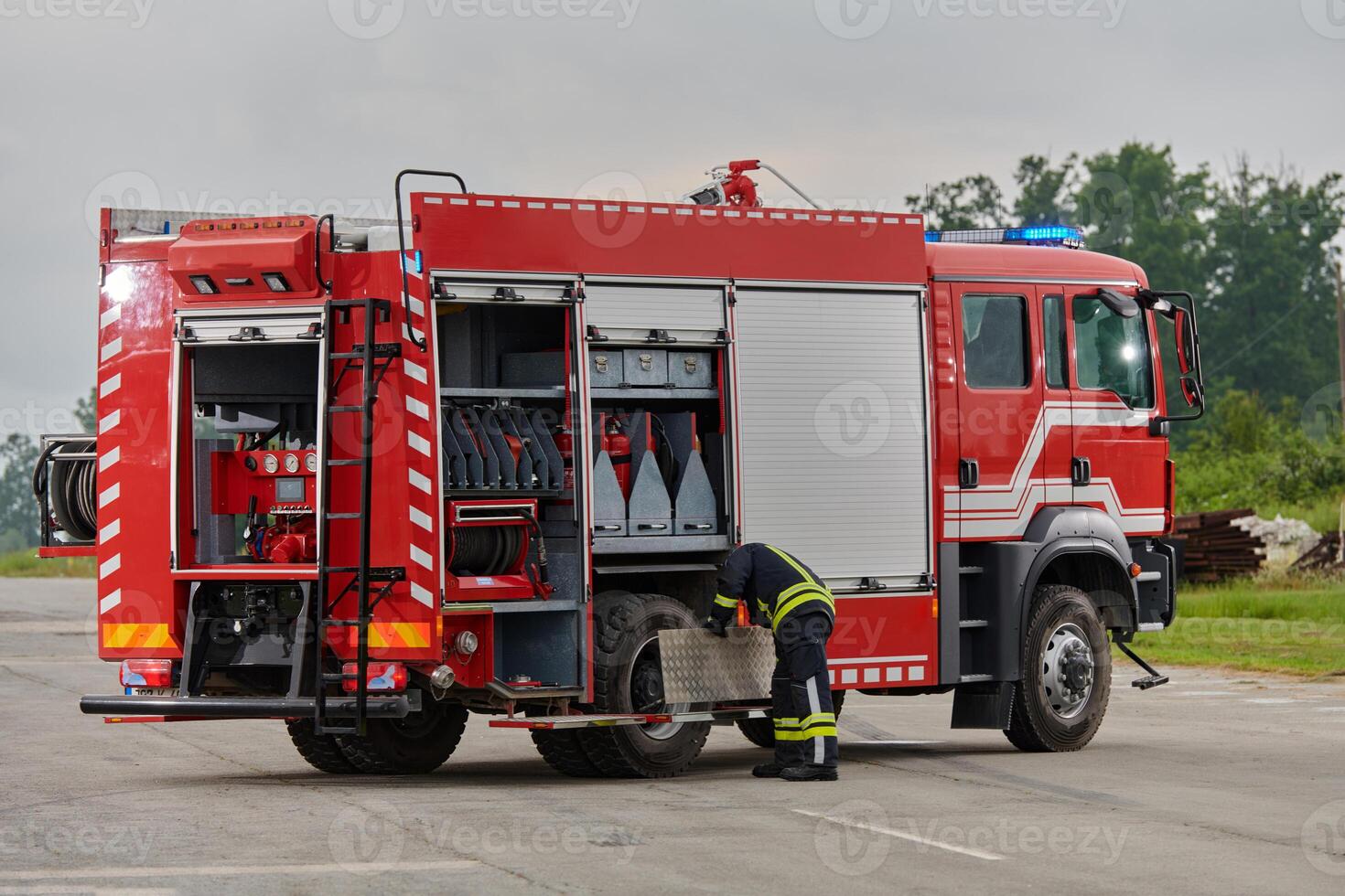 A firefighter meticulously prepares a modern firetruck for a mission to evacuate and respond to dangerous situations, showcasing the utmost dedication to safety and readiness in the face of a fire photo