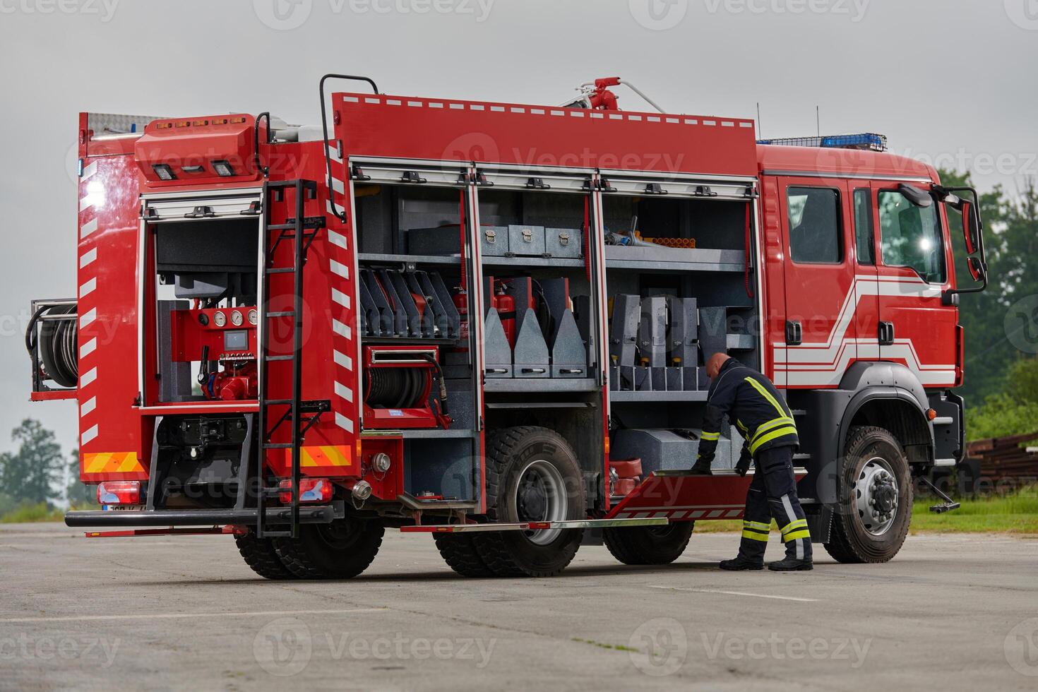 A firefighter meticulously prepares a modern firetruck for a mission to evacuate and respond to dangerous situations, showcasing the utmost dedication to safety and readiness in the face of a fire photo