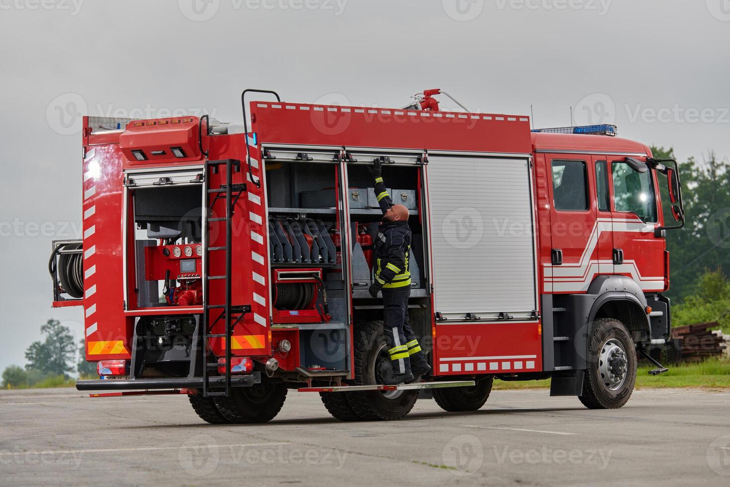 A firefighter meticulously prepares a modern firetruck for a mission to evacuate and respond to dangerous situations, showcasing the utmost dedication to safety and readiness in the face of a fire photo