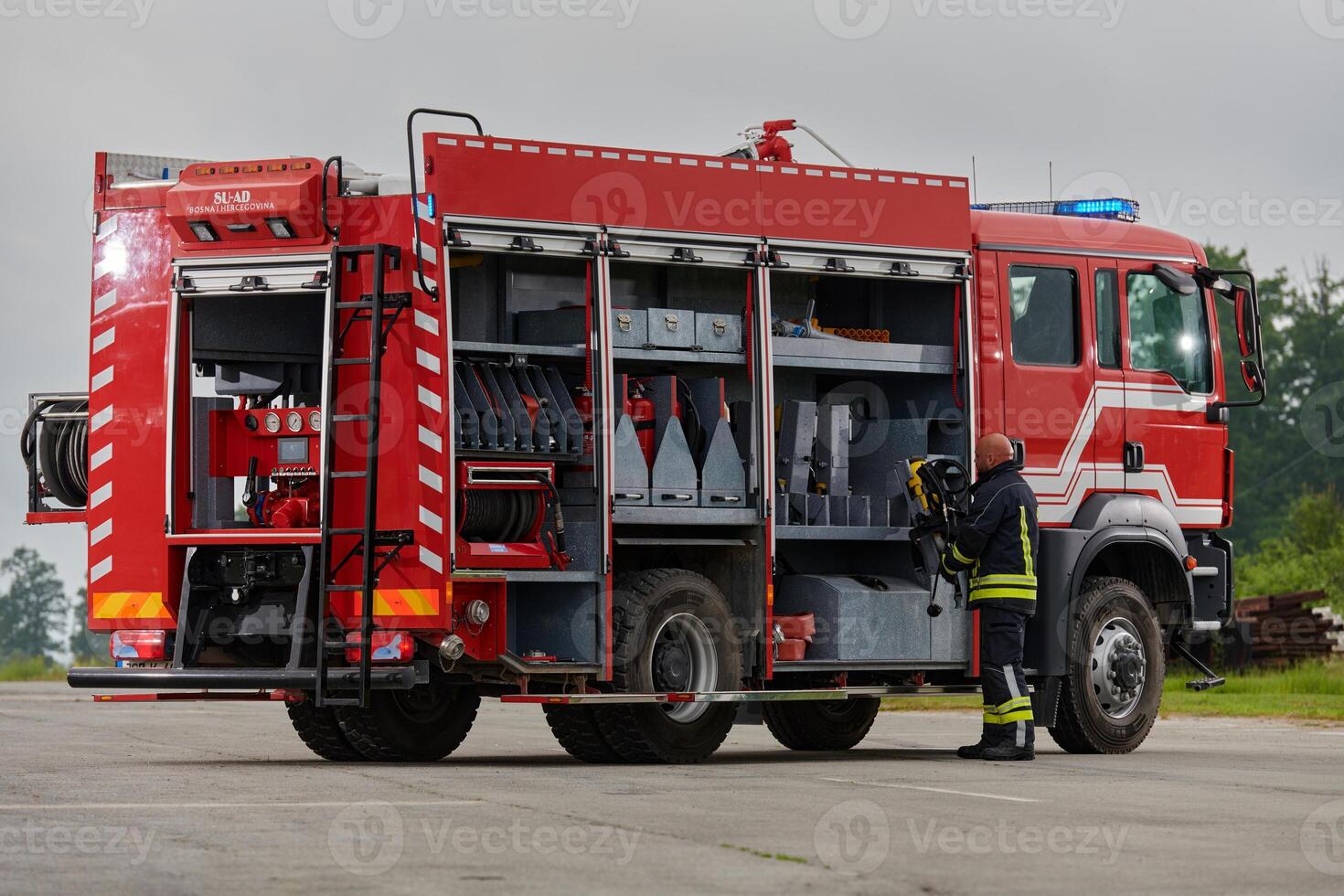 A firefighter meticulously prepares a modern firetruck for a mission to evacuate and respond to dangerous situations, showcasing the utmost dedication to safety and readiness in the face of a fire photo