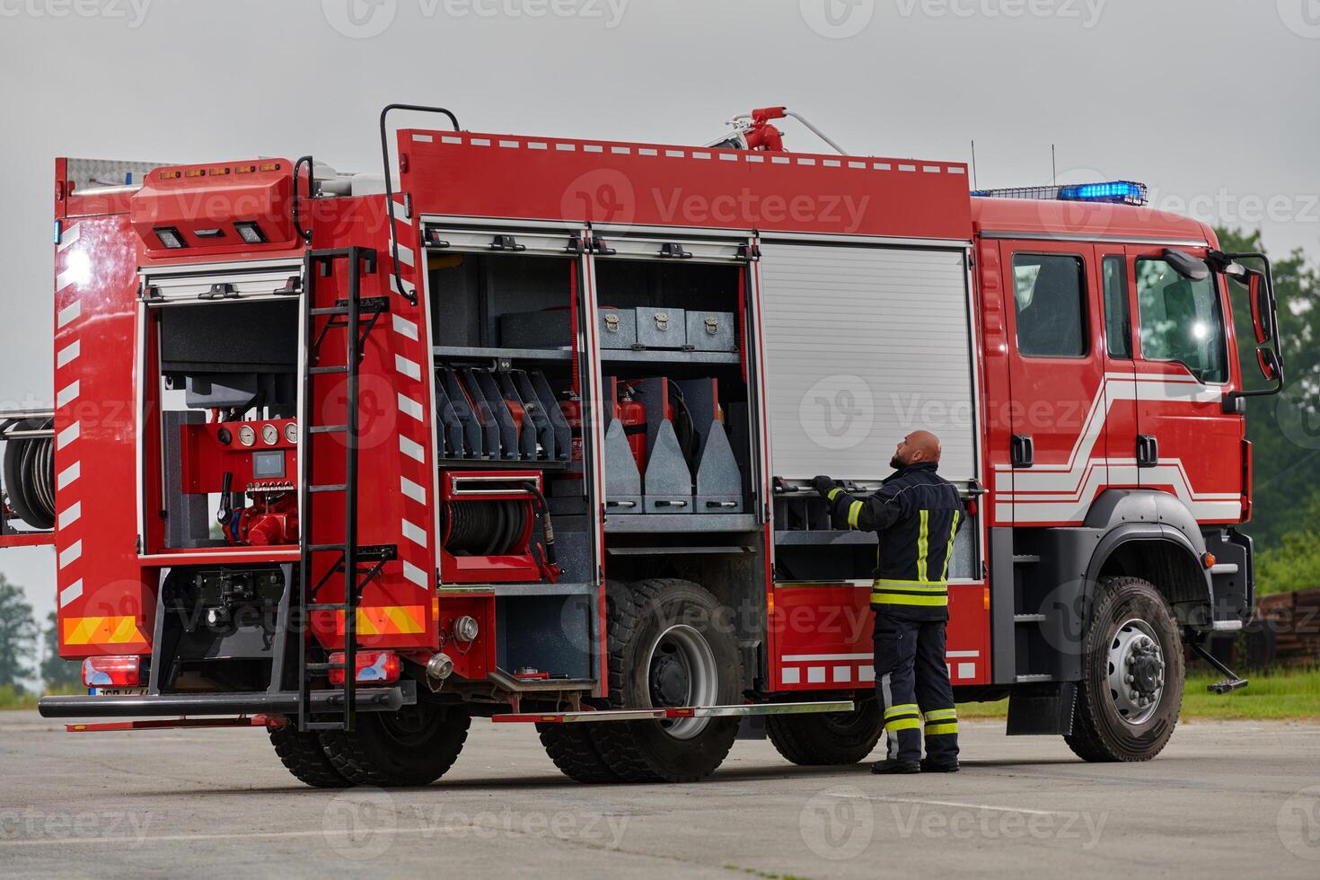 A firefighter meticulously prepares a modern firetruck for a mission to evacuate and respond to dangerous situations, showcasing the utmost dedication to safety and readiness in the face of a fire photo