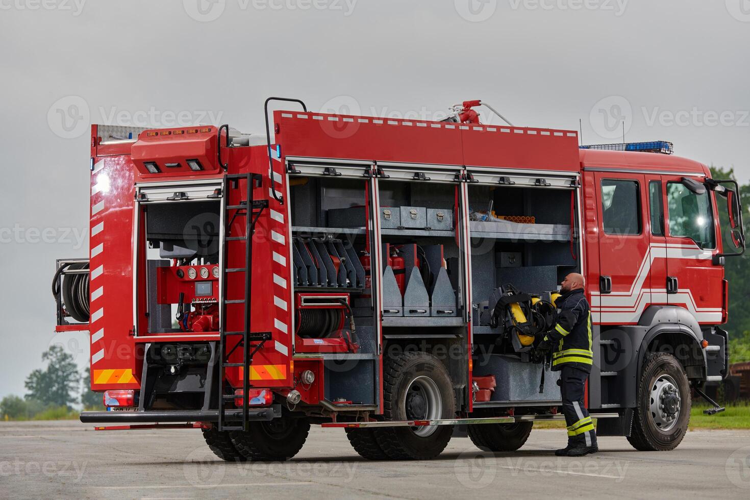 A firefighter meticulously prepares a modern firetruck for a mission to evacuate and respond to dangerous situations, showcasing the utmost dedication to safety and readiness in the face of a fire photo