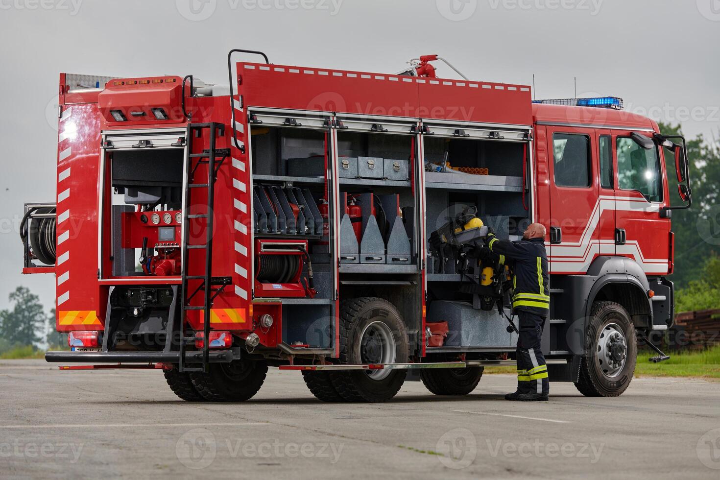 A firefighter meticulously prepares a modern firetruck for a mission to evacuate and respond to dangerous situations, showcasing the utmost dedication to safety and readiness in the face of a fire photo