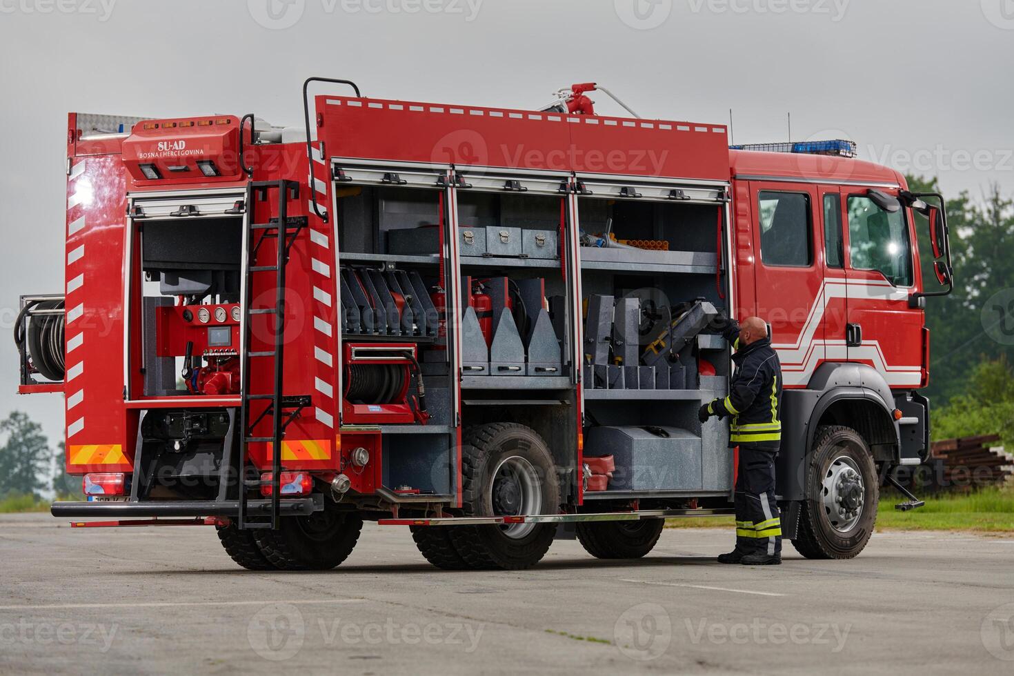A firefighter meticulously prepares a modern firetruck for a mission to evacuate and respond to dangerous situations, showcasing the utmost dedication to safety and readiness in the face of a fire photo
