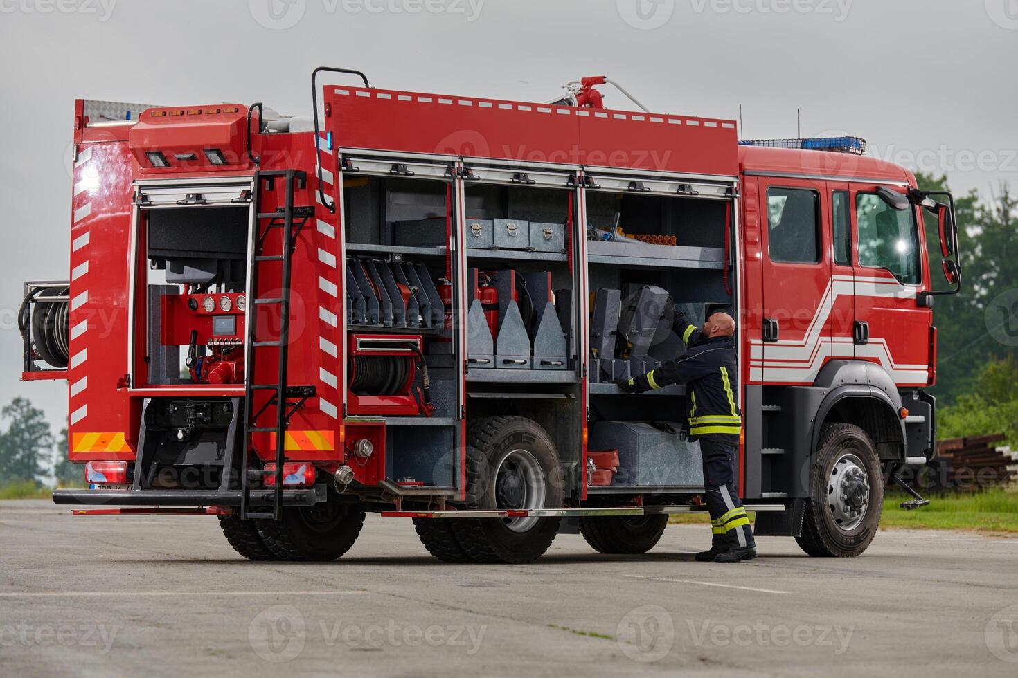 A firefighter meticulously prepares a modern firetruck for a mission to evacuate and respond to dangerous situations, showcasing the utmost dedication to safety and readiness in the face of a fire photo