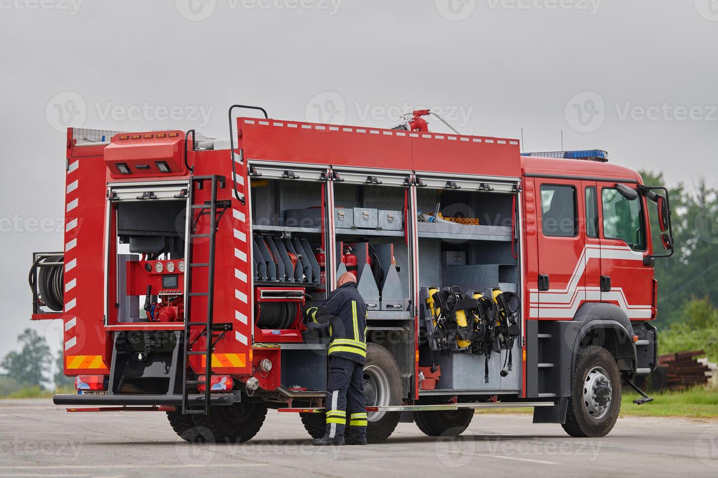 A firefighter meticulously prepares a modern firetruck for a mission to evacuate and respond to dangerous situations, showcasing the utmost dedication to safety and readiness in the face of a fire photo