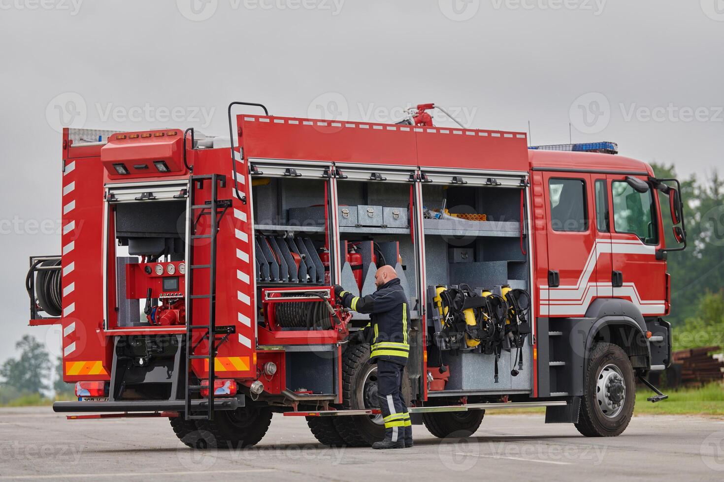 A firefighter meticulously prepares a modern firetruck for a mission to evacuate and respond to dangerous situations, showcasing the utmost dedication to safety and readiness in the face of a fire photo