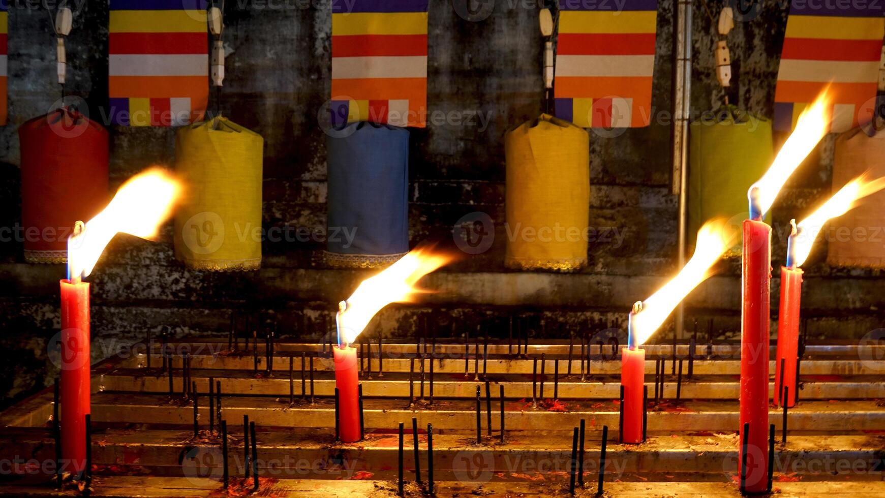 Many burning lighting candles in the temple at night photo