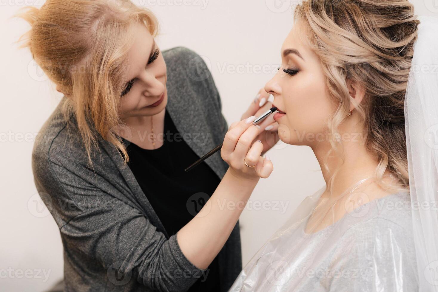 professional makeup artist paints a young girl's lips with lipstick in a beauty Studio photo