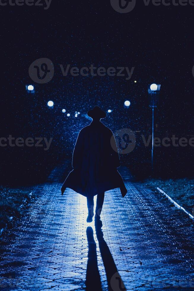 male detective in a hat and raincoat at night in a rainy city photo