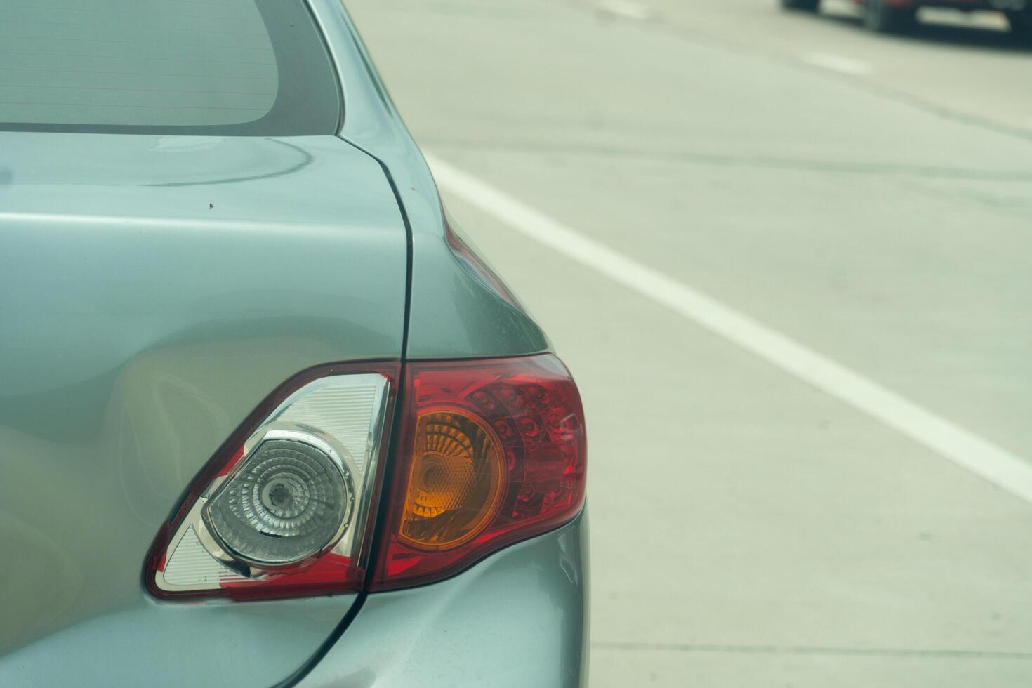 Rear side of car with smashed tail light. Car pakring beside of the road at day time. photo
