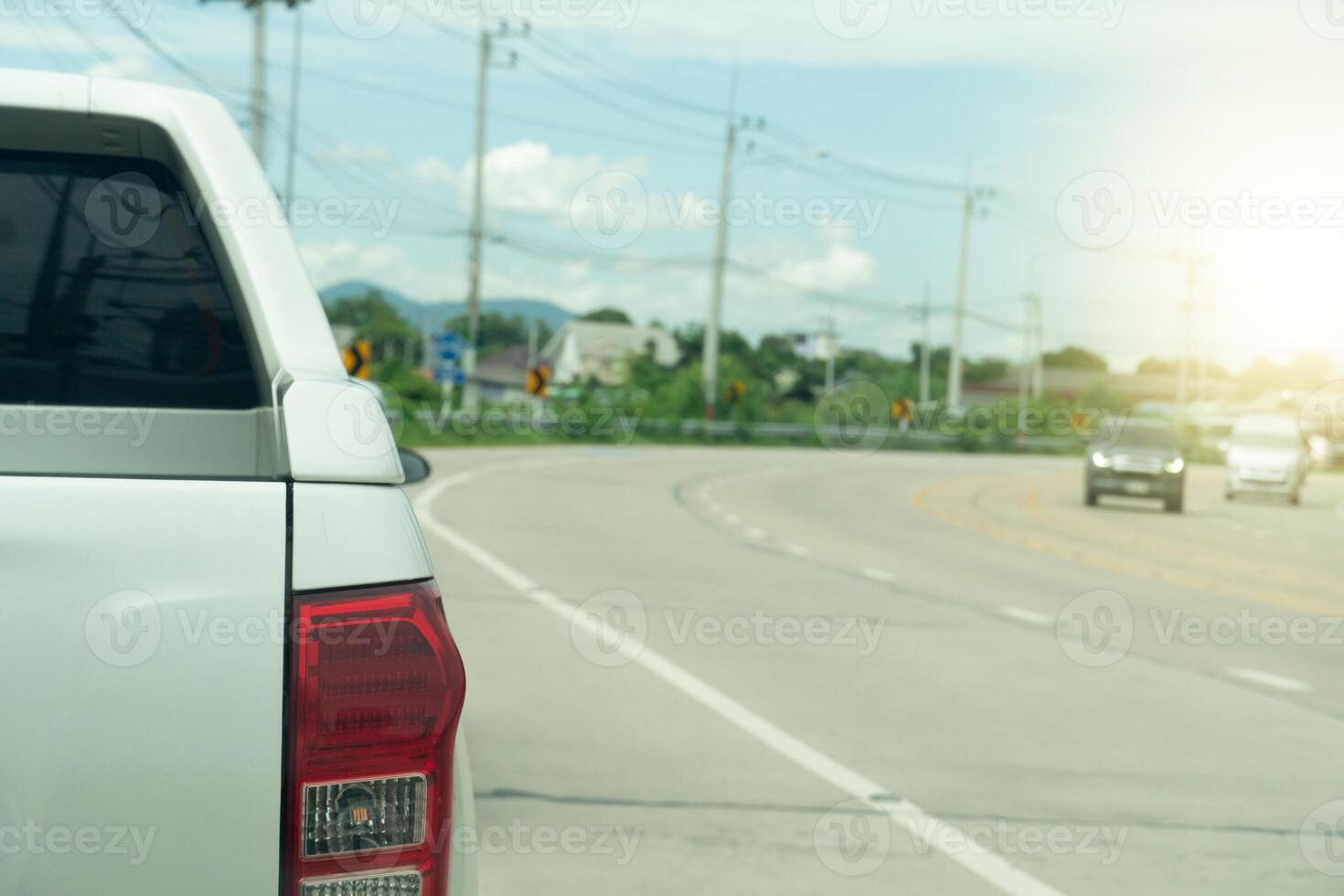 Rear side of pickup car white color parking beside of concrete road. Background of concrete path curves and traffic passes by. photo