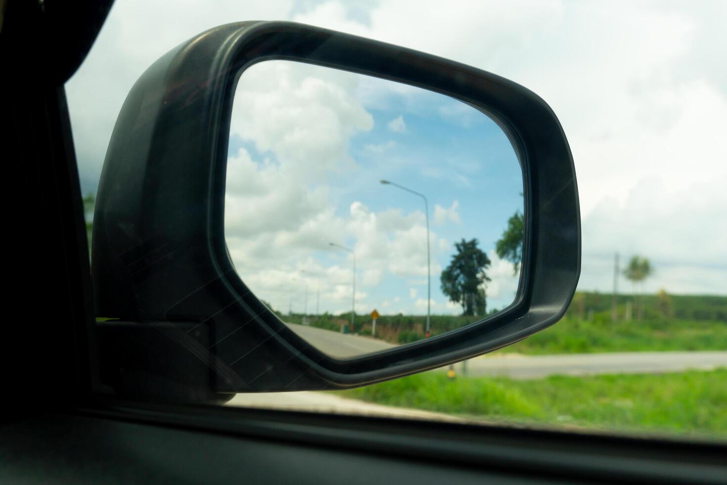 Abstract mirror wing of car. Looking back for trip to travel with green meadow meandow under blue sky. on roads without cars. photo