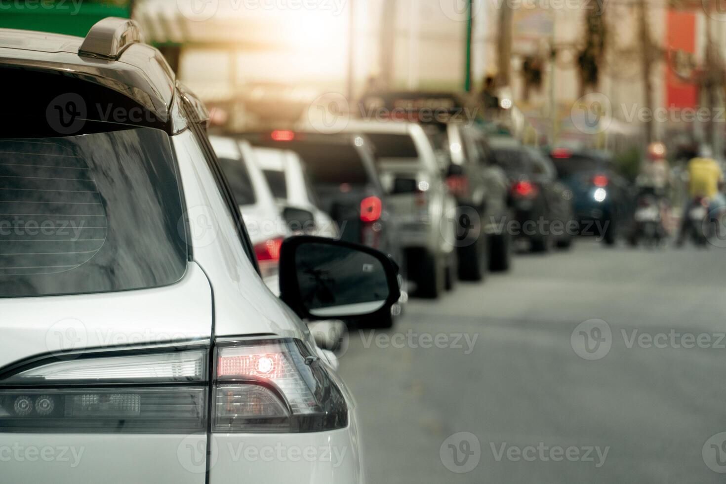 Rear side of car on the asphalt road. Cars parked in a long queue in a curve. Traffic jam in the evening time. City for background with light of sun. photo
