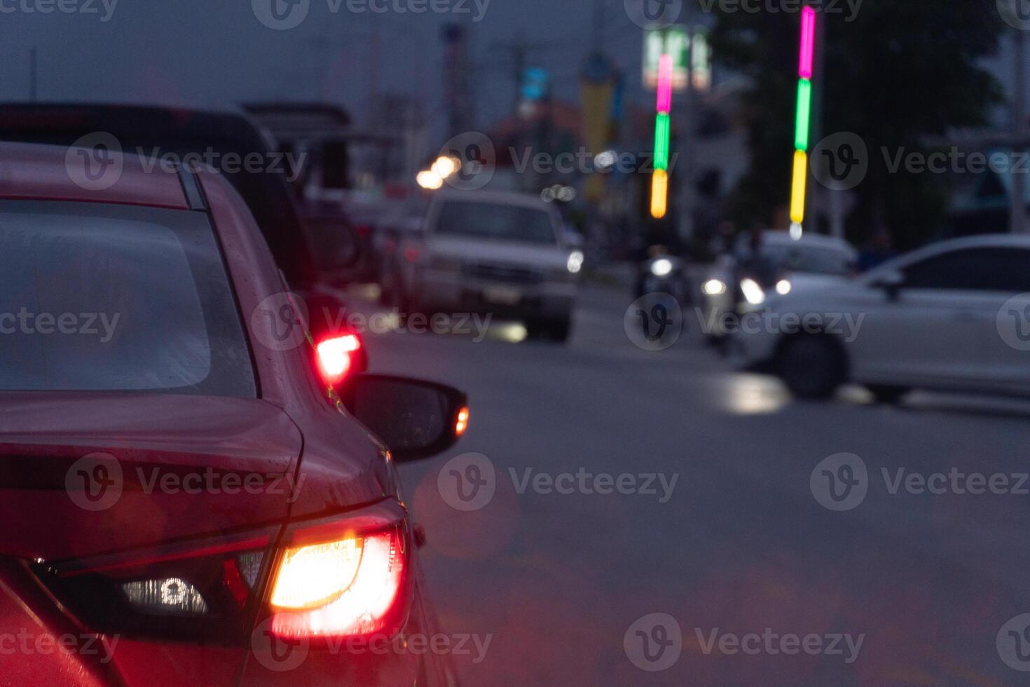 Transporting cars on the road. Turn on your brake lights and wait for the car in front drive through. All cars are wet from the rain. The atmosphere is heavy rain and gloomy lights. photo
