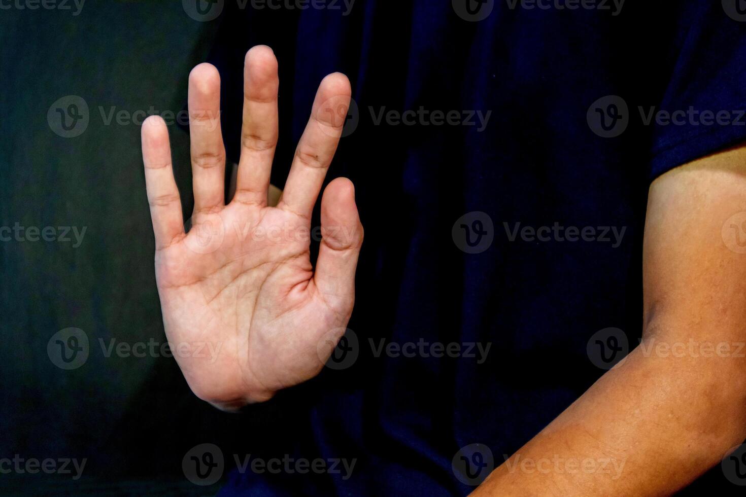 Man giving rejection sign on dark background. Signaling to Stop or refuse something. photo