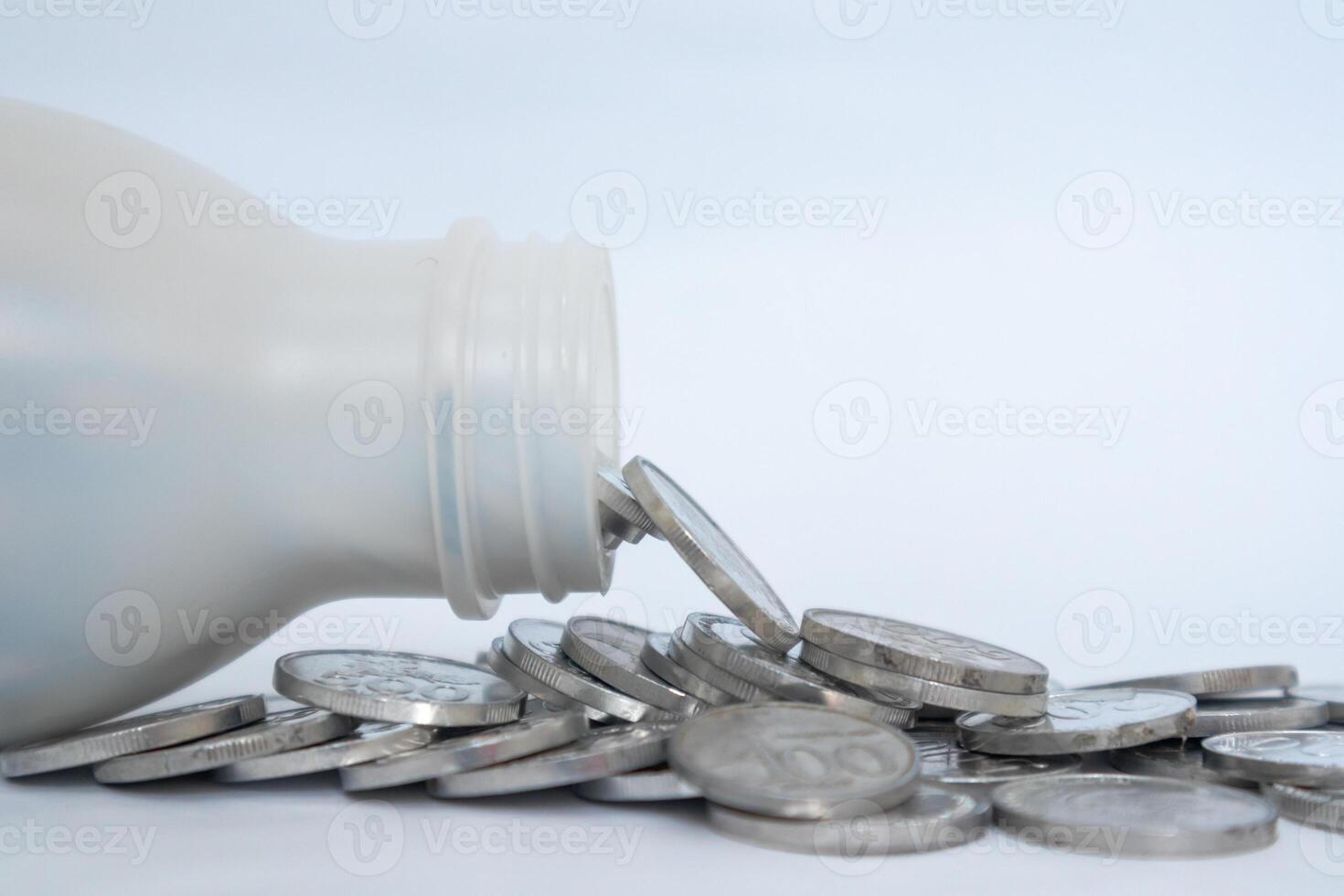 Indonesian Rupiah coins in a plastic bottle spilled on a white background. Business and finance concept. photo