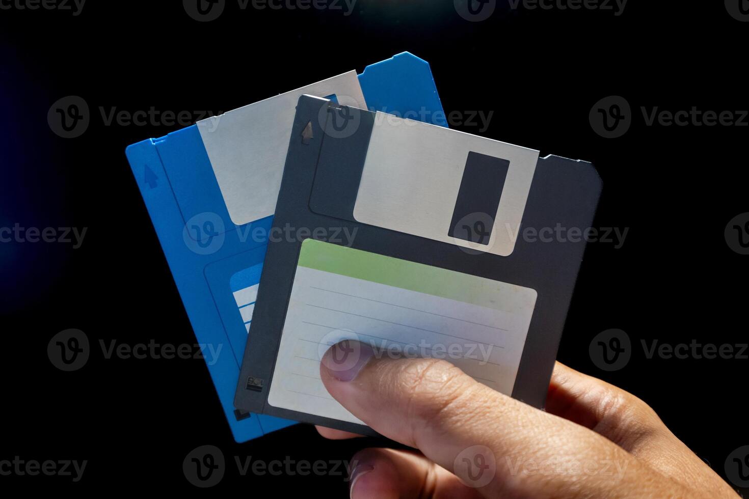 Close up view of hand holding two floppy disks on a dark background photo