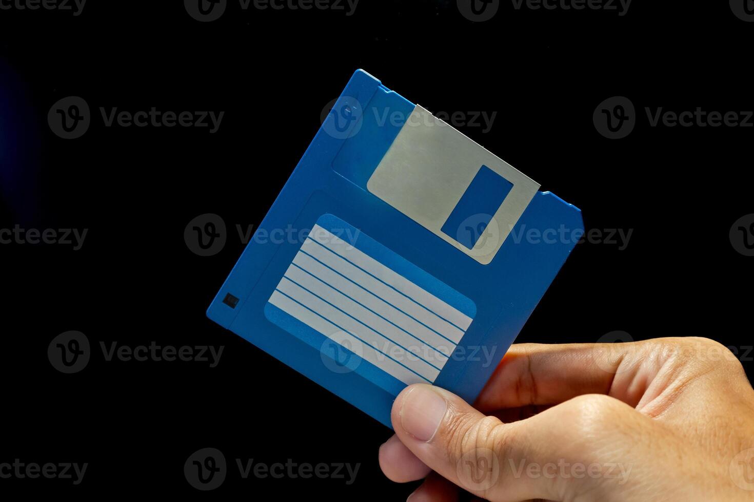 Close up view of hand holding a floppy disk on dark background photo