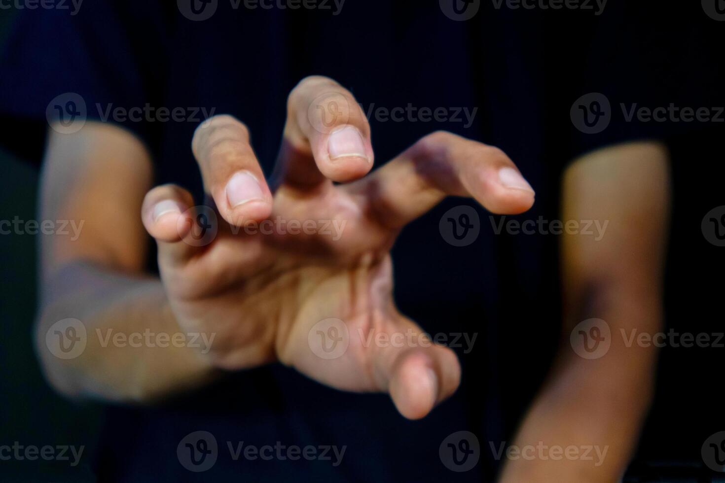 Man with gripping pose to catch something on black background. Trying to grab something. photo