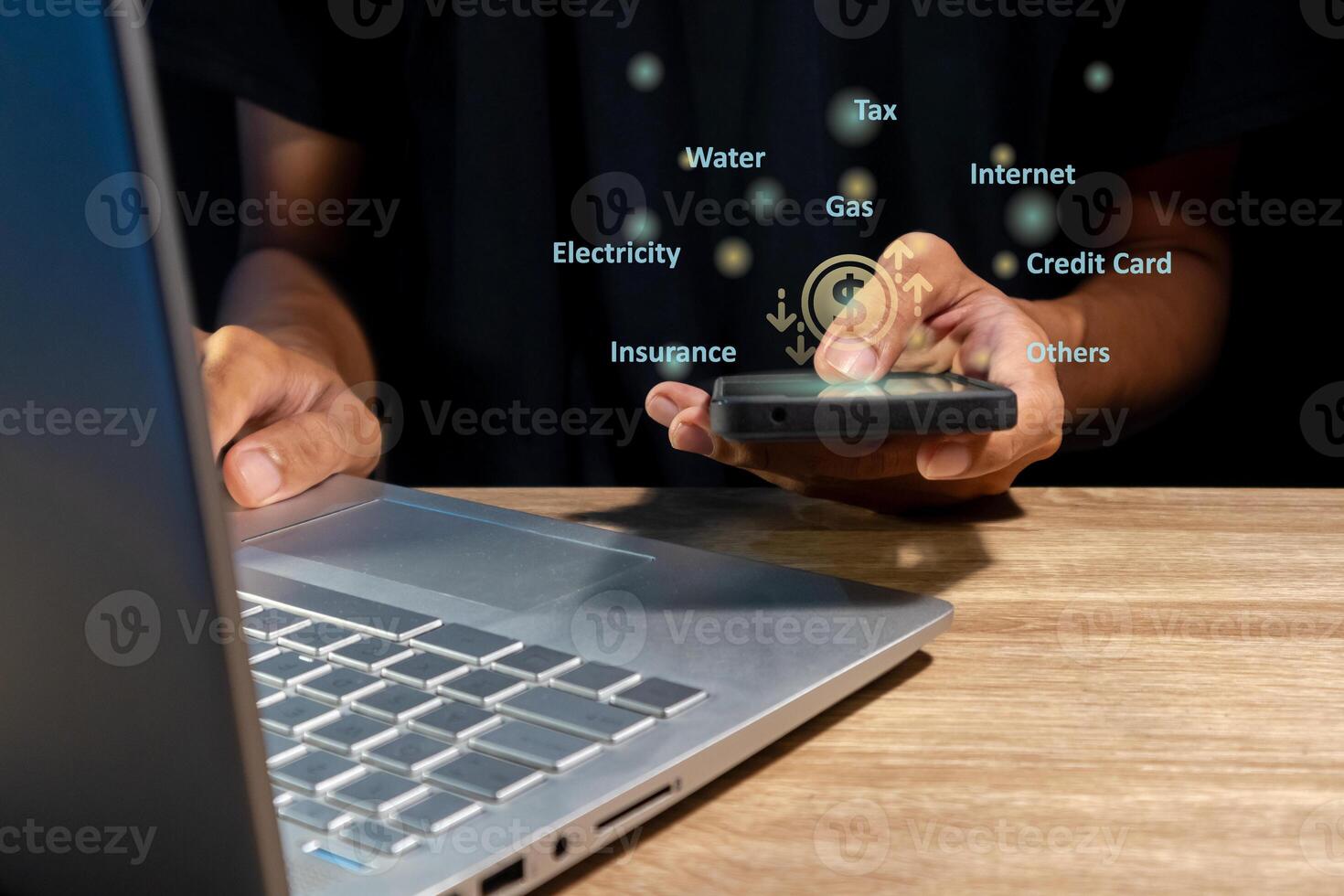 Man using a laptop and holding a smartphone to calculate the monthly bills or household expenses photo