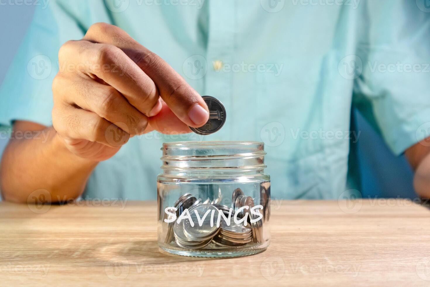 Man puts an Indonesian Rupiah coin into a glass jar for a savings photo
