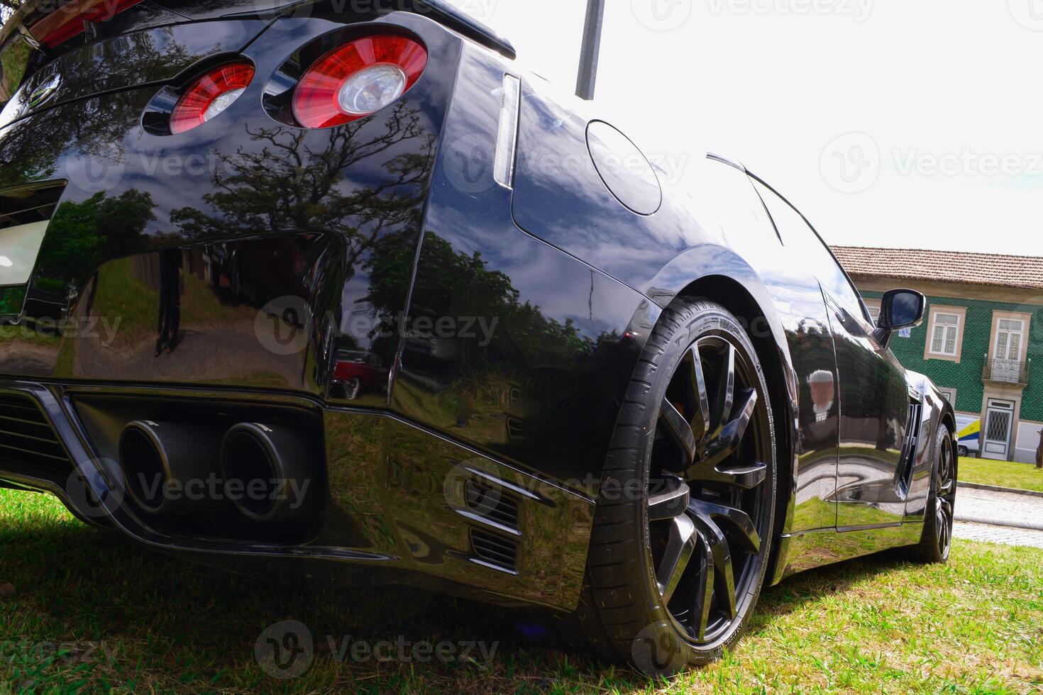 Rear view of a black modern expensive car that stands on a green lawn. photo