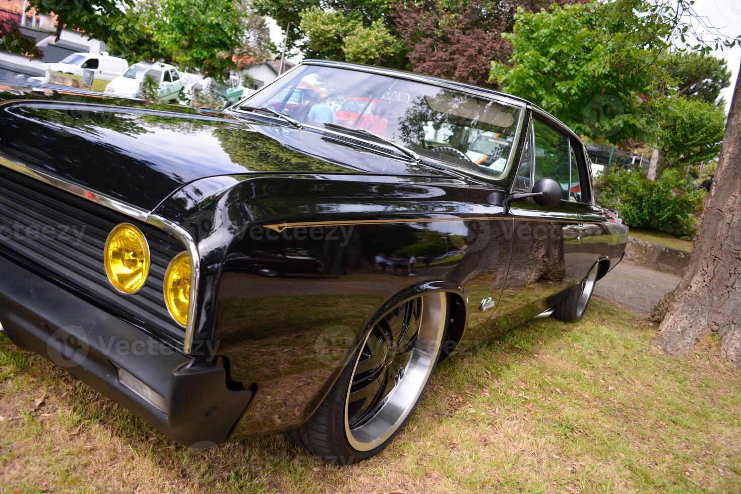 Round yellow headlights of a black retro car with a shiny polished body. photo