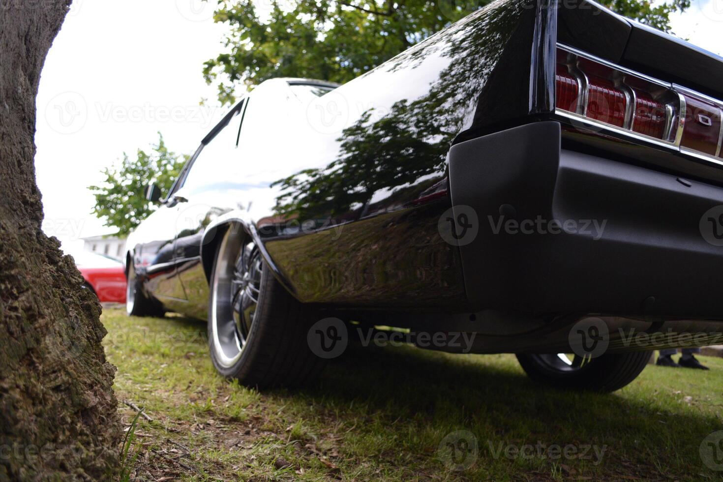 A luxury car in retro style is waiting for its owner on the grass in front of the house. photo