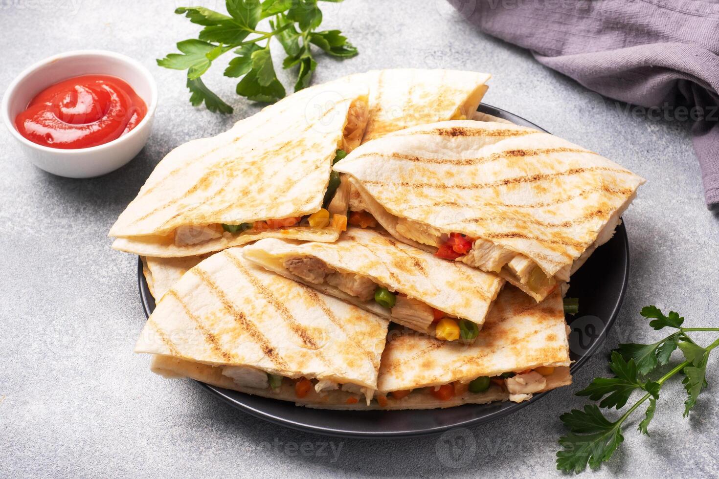 Triangular slices of a Mexican quesadilla with the sauce. The traditional dish of Mexico is tortillas stuffed with meat and vegetables. copy space. photo
