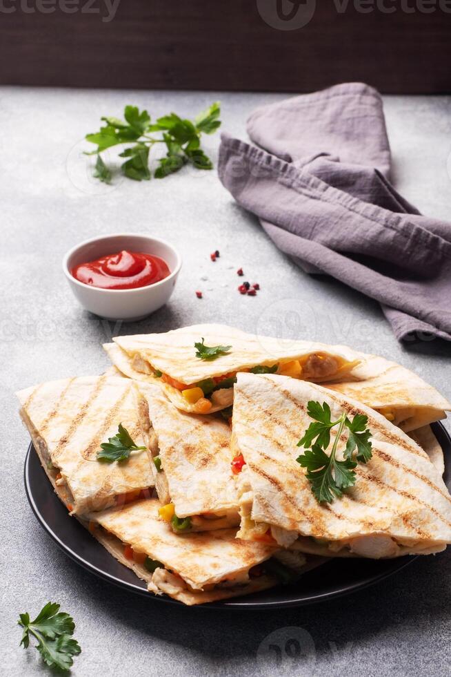 Triangular slices of a Mexican quesadilla with the sauce. The traditional dish of Mexico is tortillas stuffed with meat and vegetables. copy space. photo