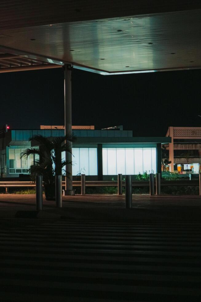 shows a view of a modern building at night, with a large window that is brightly lit. The building is located in an airport area, and the scene is quiet and peaceful. photo
