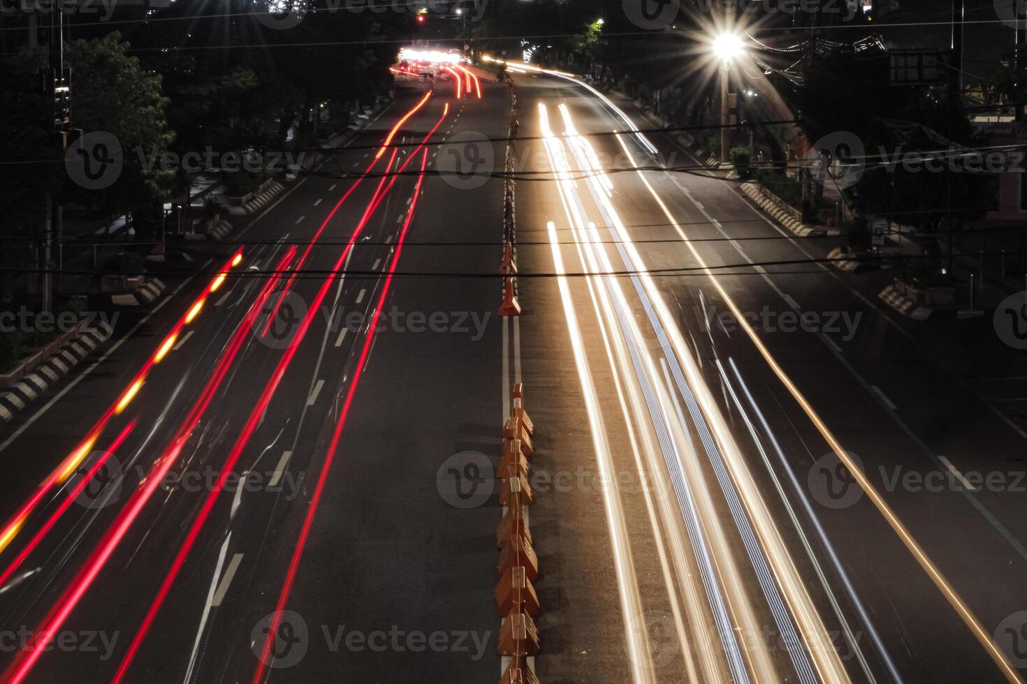 a long exposure shot of a busy city street at night. The headlights and taillights of cars create streaks of light, creating a sense of movement and energy. photo