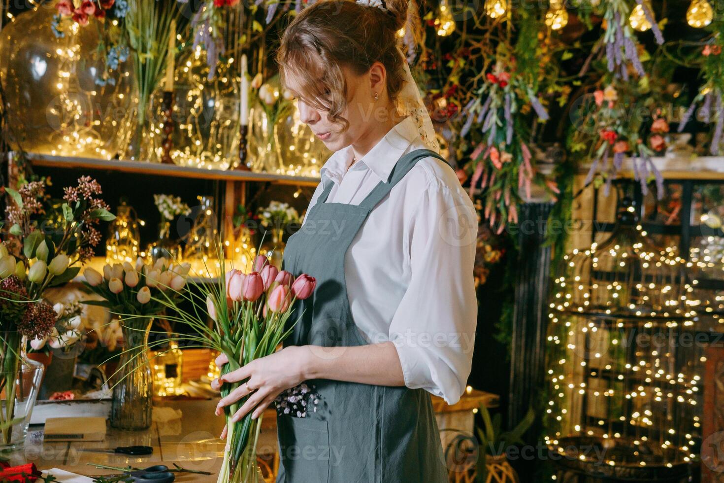 A woman in her florist shop collects bouquets of flowers. The concept of a small business. Bouquets of tulips for the holiday on March 8. photo