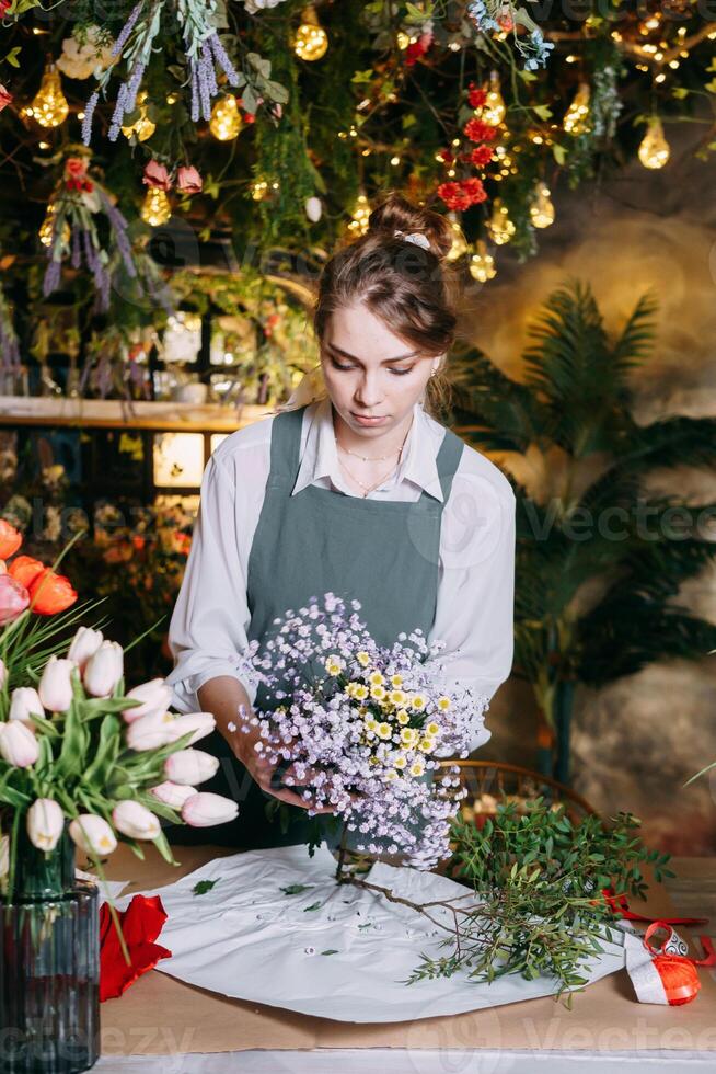 A woman in her florist shop collects bouquets of flowers. The concept of a small business. Bouquets of tulips for the holiday on March 8. photo