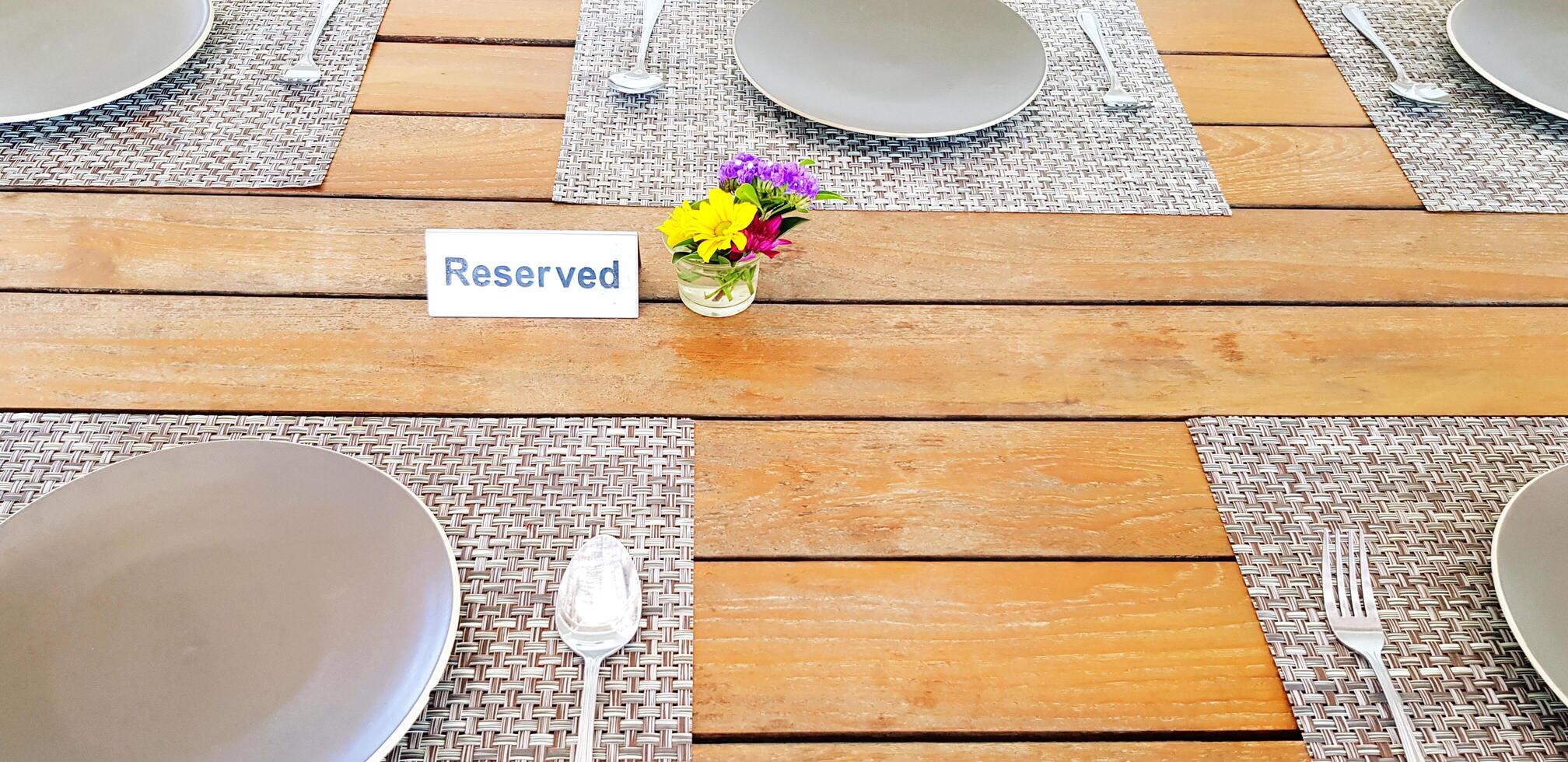 Gray Plate with spoon and fork putting on wooden table for customers to eating food and reserved with beautiful flower in decorated and copy space at restaurant. Preparation and Service photo